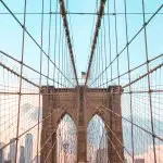 See the majestic view of Lady Liberty atop the Brooklyn Bridge.